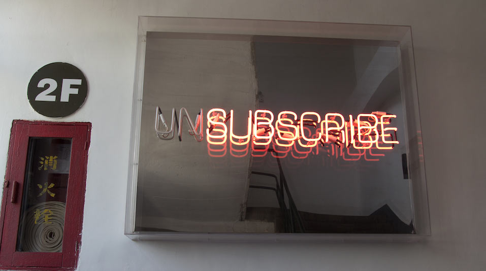 A neon sign with subscribe lit and the prefix un not lit
