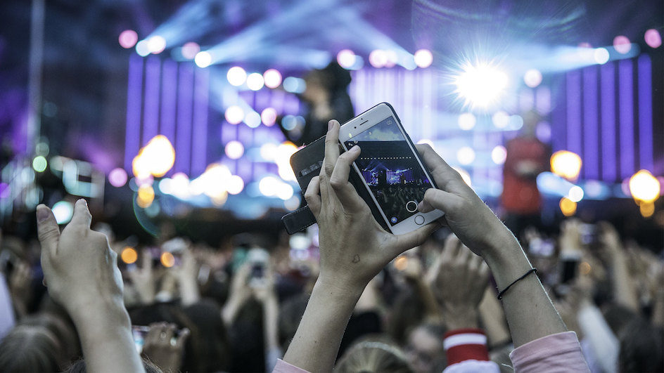 Concert goers in Norway take a photo with their mobile phone.
