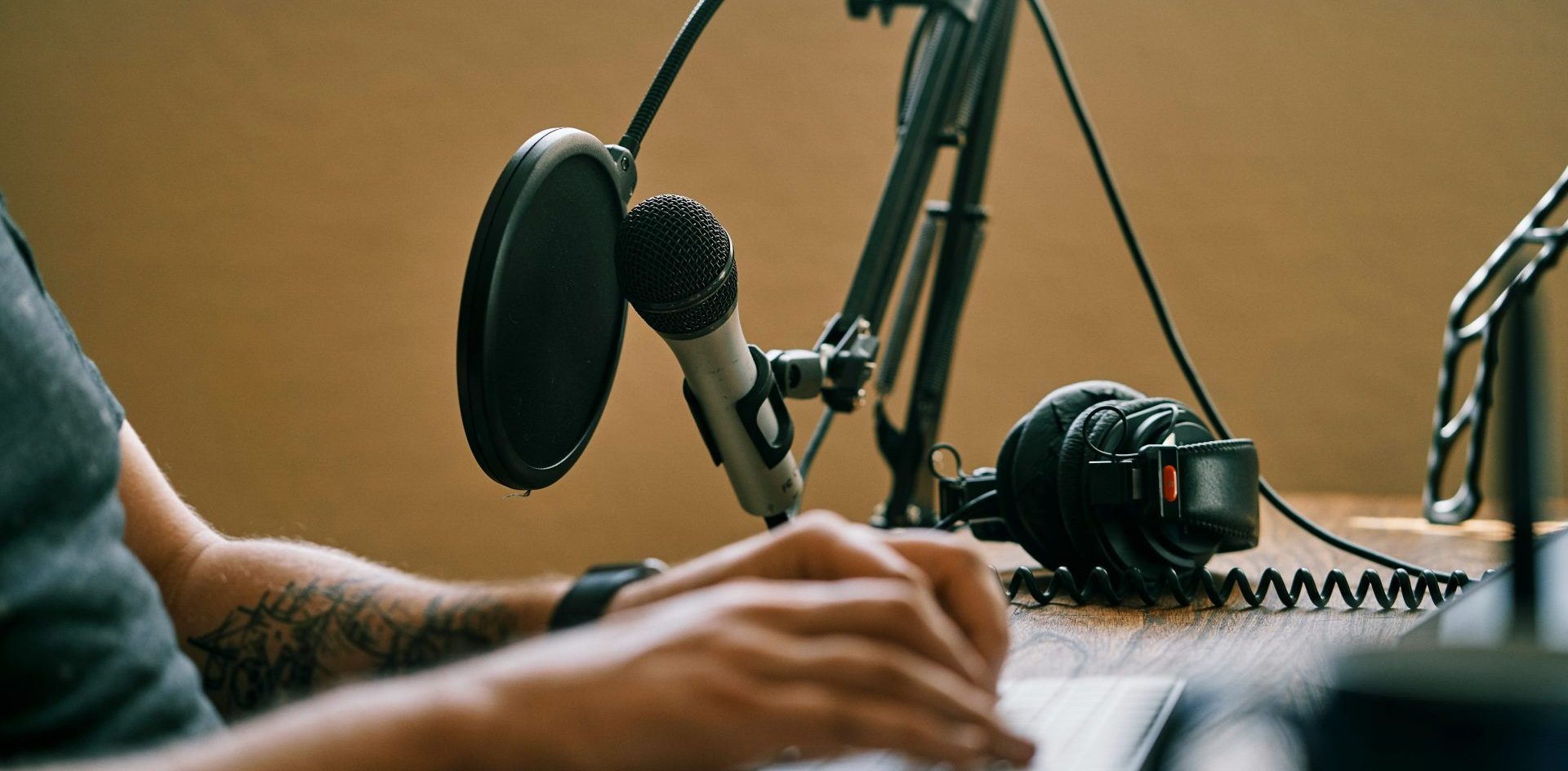 A person sits at a computer with a microphone while recording a podcast. Image by ConvertKit from Unsplash Publishers are finding that listeners to their podcasts have a completion rate of up to 90%.
